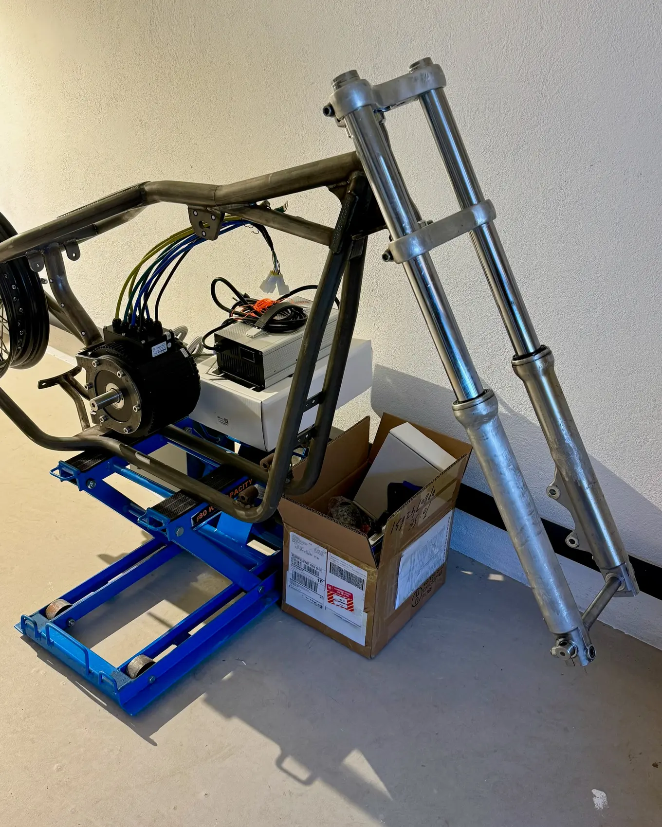 A pair of fork legs standing against the frame on the lift