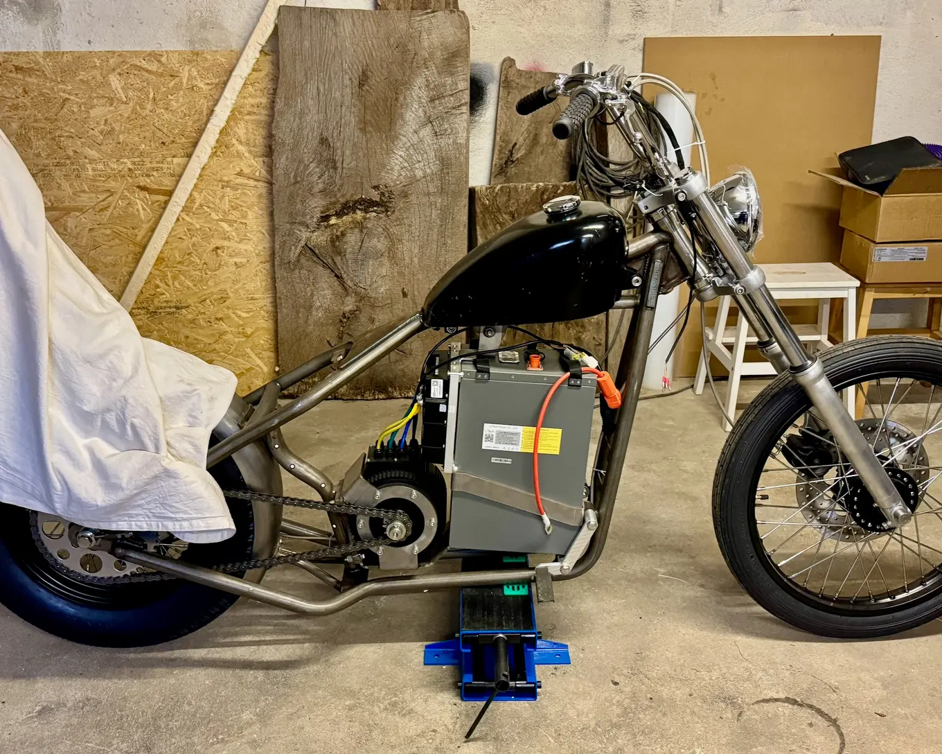 The bike under a white sheet beside the garage door