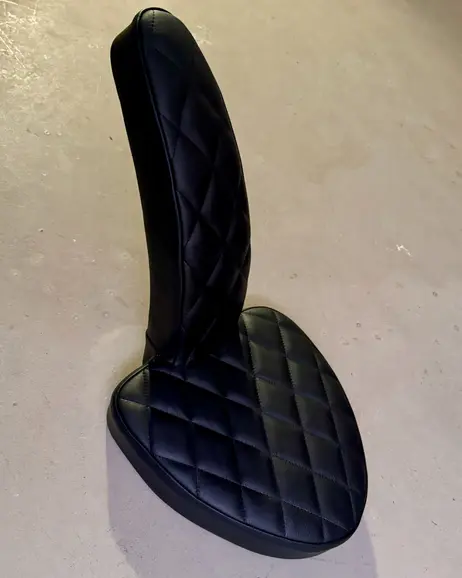 The upholstered seat, diamond stitched, standing on the floor