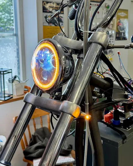 The headlight lit, seen from beside the front wheel