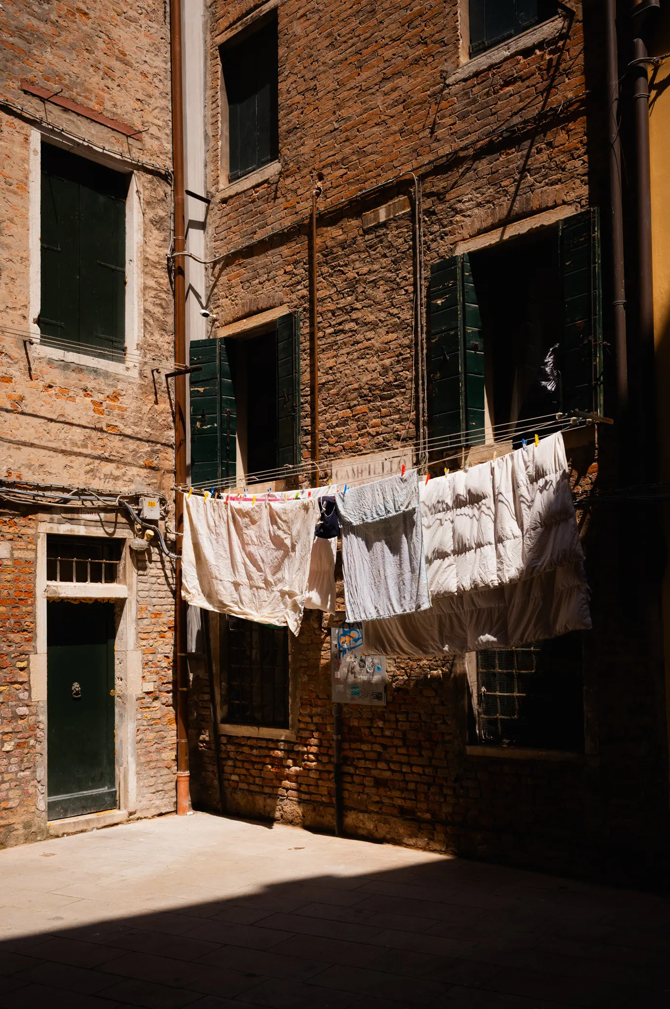 Washing strung across a narrow brick courtyard in the sun