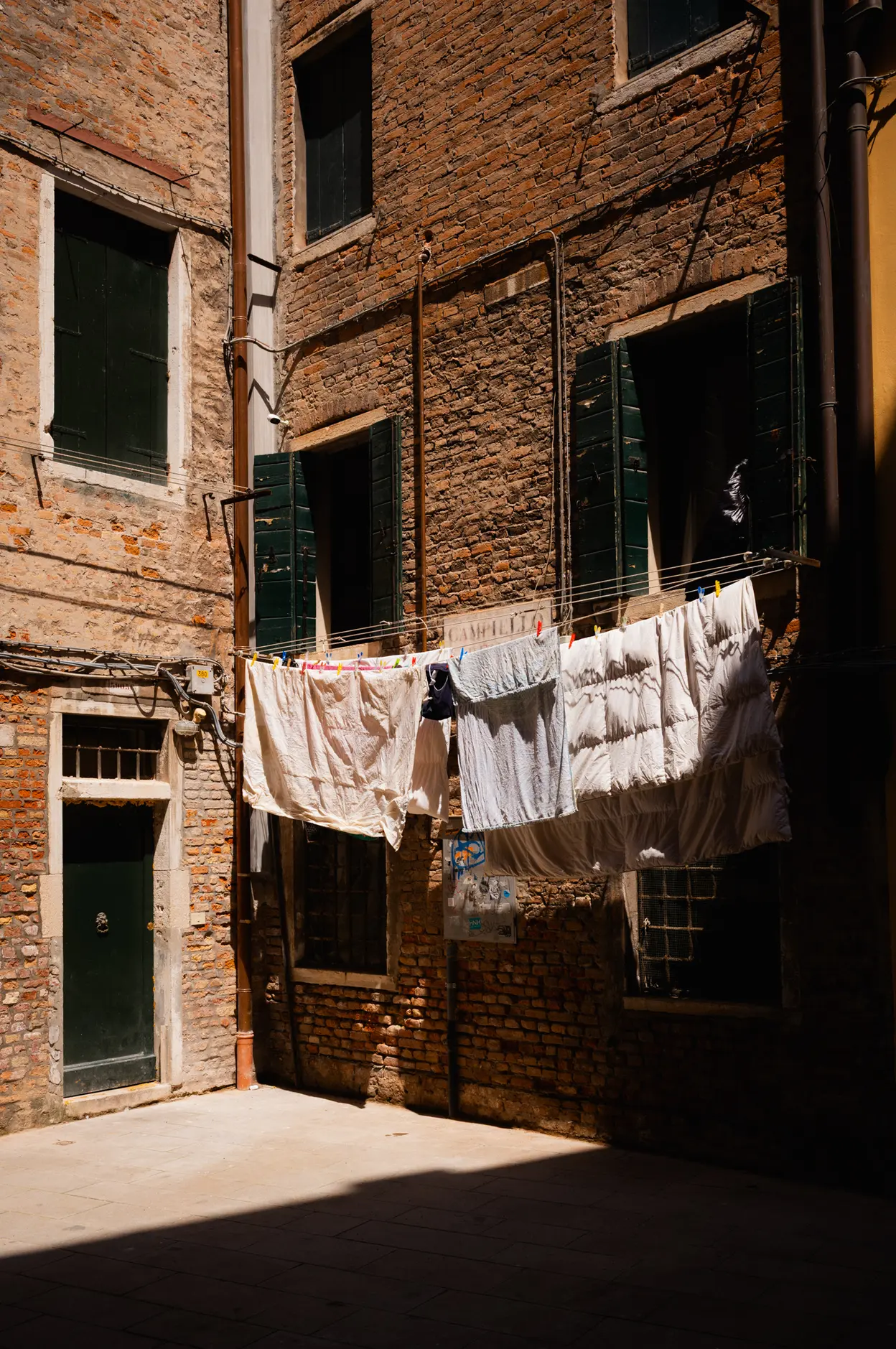 Washing strung across a narrow brick courtyard in the sun
